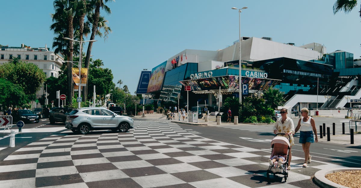 Vue diurne de la promenade de Cannes avec casino, passants et palmiers.